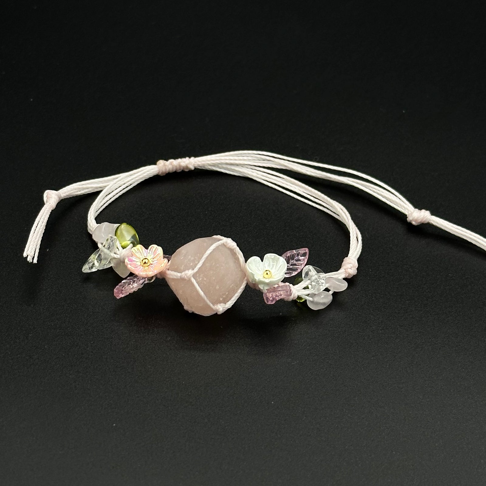 Rose Mist bracelet with pink and mixed-color blossom stones on a hand-braided cord