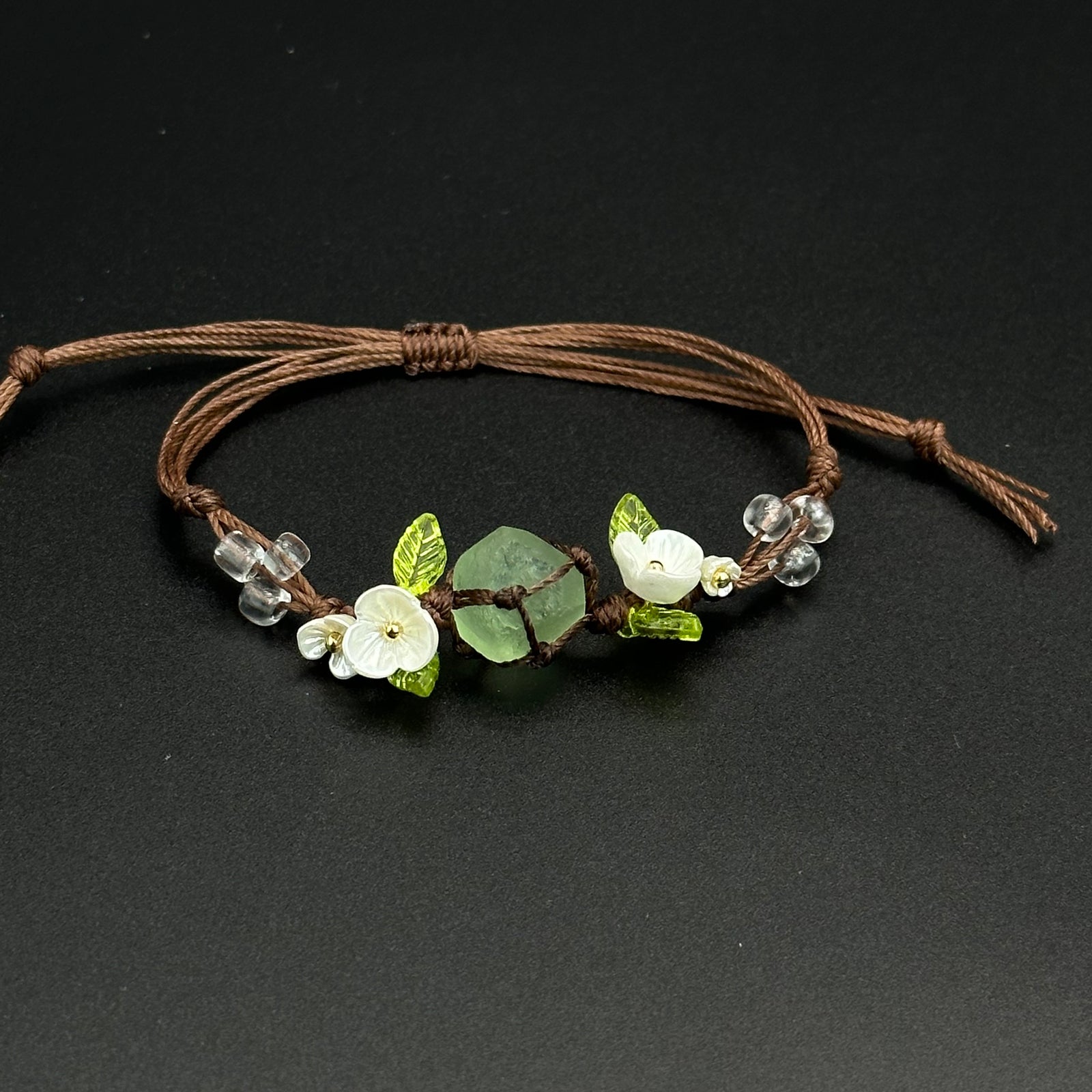 Lily Meadow bracelet with green and pale leaf-inspired crystals on a hand-braided cord