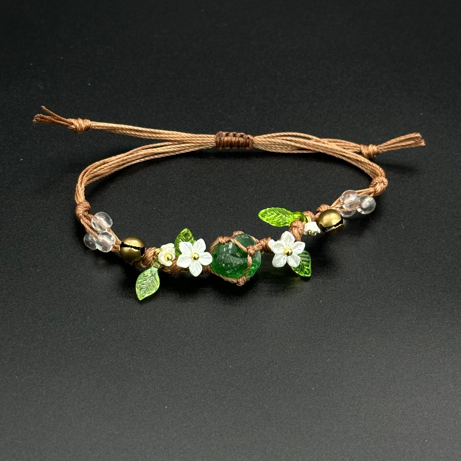 Emerald Wildflower bracelet with green leaf-shaped crystal accents on a hand-braided cord