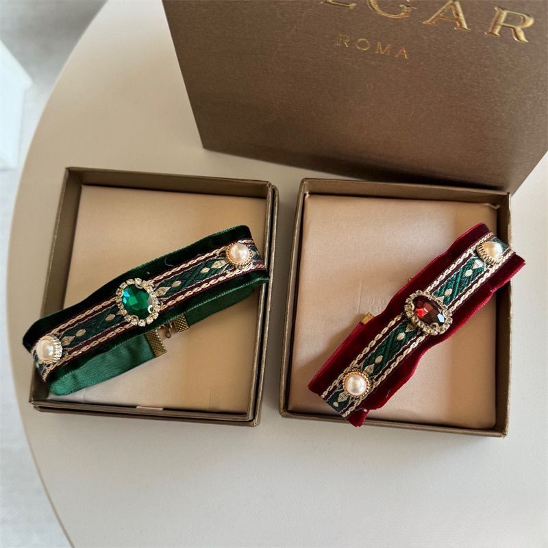 Green and red velvet jewel collars displayed in boxes